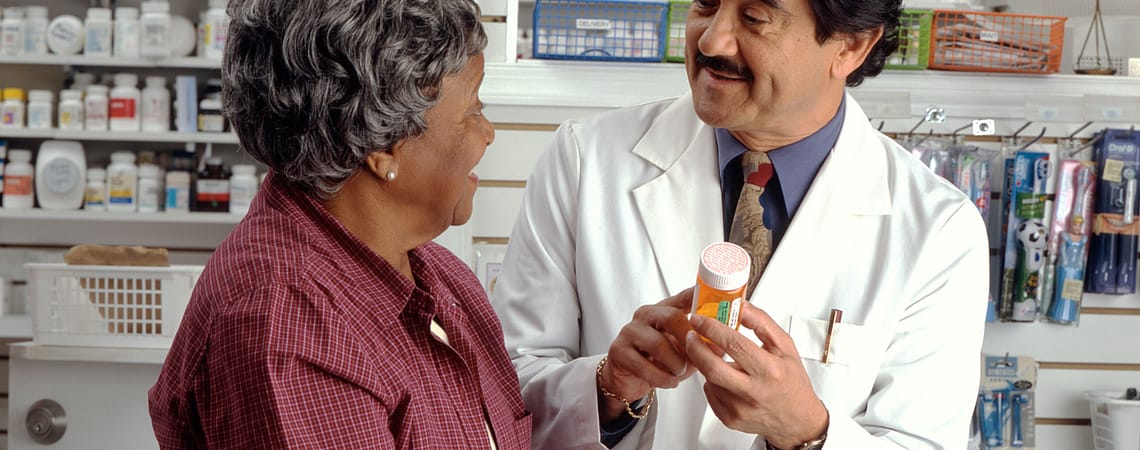 A pharmacist holding a medicine facing to an older lady