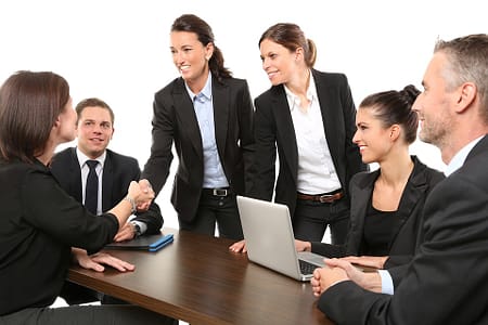 A smiling woman shaking hands of another woman