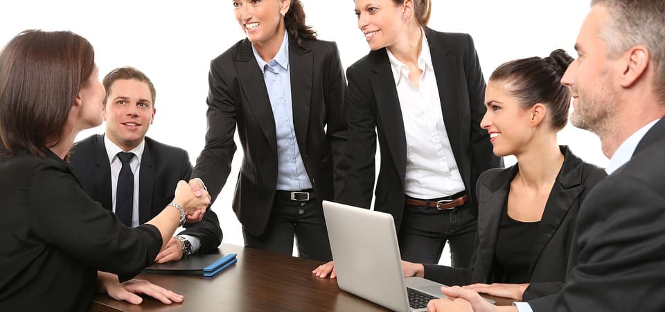 A smiling woman shaking hands of another woman
