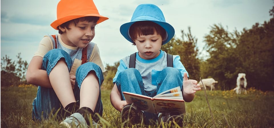 two boys outdors reading